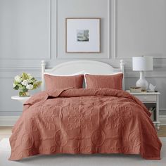 a bed with an orange comforter and pillows