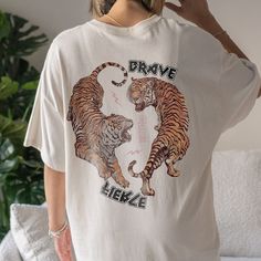 "Tiger Graphic Tee Yin Yang Shirt Good Energy Shirt Fearless Shirt Year Of The Tiger T Shirt Trendy Shirts For Women Y2k Shirt Tiger Shirt ➭ How to Order 1. Choose your shirt size & color options. 2. Select the quantity. 3. Click \"Add to Cart.\" 4. Listen for a knock at your door! ➭ Care Instructions Wash your shirt inside-out in cold water. Do not bleach, dry clean, or iron directly on the design. Tumble dry on low. ➭ Production & Shipping Processing typically takes 1-3 days. Depending on wher Trendy Tops With Front And Back Print, Casual White Shirt With Front And Back Print, Casual White Shirt With Print, Y2k Relaxed Fit Shirt With Letter Print, Casual Cotton Shirt With Front And Back Print, Casual Crew Neck Top With Front And Back Print, Trendy Short Sleeve Top With Front And Back Print, Graphic Tee Shirt With Front And Back Print, Trendy Oversized Tops With Front And Back Print