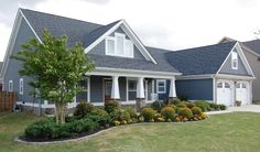 a blue house with white trim on the front and side windows is surrounded by green grass