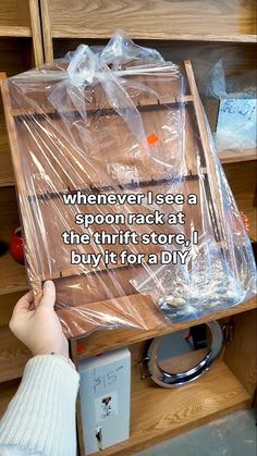 a person is holding a box with plastic on it and the words, whenever i see a spoon rack at the thrift store, i buy it for a diy