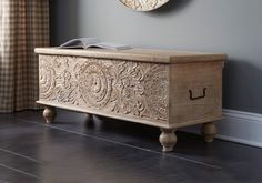 a wooden chest sitting on top of a hard wood floor next to a wall with a clock above it