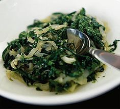 a white bowl filled with greens and a spoon