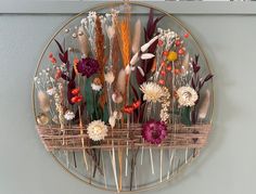 an arrangement of dried flowers in a basket on a wall