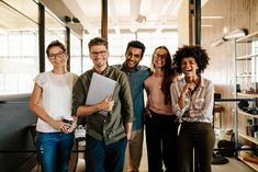 a group of young people standing together in an office smiling and posing for the camera