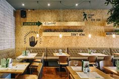 an empty restaurant with wooden tables and chairs, hanging planters on the wall above them