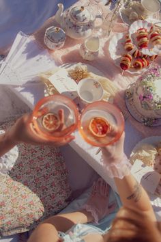 two people toasting at a table with tea and pastries on it