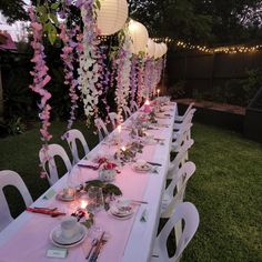 a long table is set up with plates and candles for an outdoor dinner in the evening