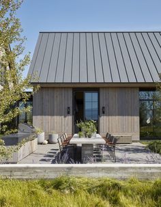 an outdoor dining area in front of a house with wooden sidings and metal roof