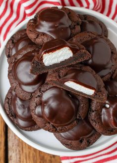 chocolate cookies with marshmallows in the middle on a white plate, next to a red and white striped napkin