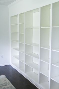 an empty room with white bookcases in it