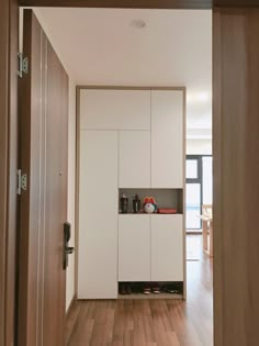 an empty hallway with white cabinets and wooden floors