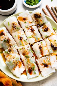 a plate filled with dumplings and chopsticks next to some dipping sauce on the side