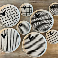 six plates with black and white designs on them sitting on a wooden table next to each other