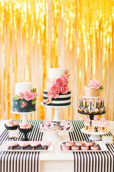 a table topped with cakes and cupcakes covered in frosting on top of black and white stripes