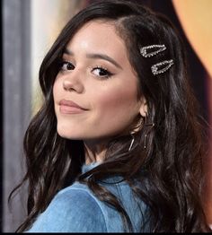 a close up of a person with long hair and earrings on her head, looking off to the side