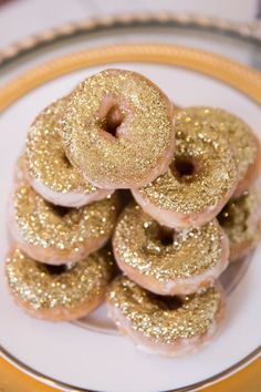 there are many donuts on the plate with gold sprinkles and frosting