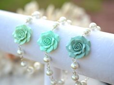 "Featuring Hand sculpted Mint Green Rose Bracelet. The listing is for one bracelet. There are 3 choice of colors to choose from : 1. Light Mint Green. 2. Mint Green. 3. Dusty Mint Green. Matching ewelry available in my shop. MATERIAL AND SIZE: Flower size is approximately 25-26mm across 8mm White pearls (pictured). Glass pearls and Swarovski available. Silver Plated Chain (pictured), antiqued brass, gold plated wire available, drop a note if you prefer different type of wire. The entire length i Rose Flower Bracelet, Mint Green Jewelry, Mint Green Bridesmaids, Collar Rosa, Asymmetrical Necklace, Pearl Rose, Rose Bracelet, Green Bridesmaid, Flower Green