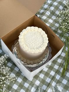 a cake sitting in a box on top of a checkered tablecloth covered table