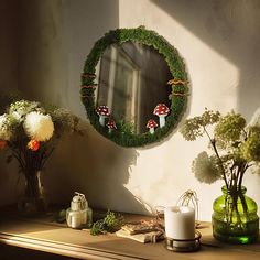 a mirror sitting on top of a wooden table next to vases with flowers in them