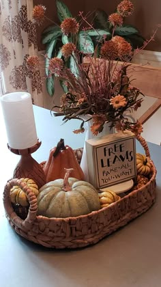 a basket filled with pumpkins, candles and other fall decorations on top of a table