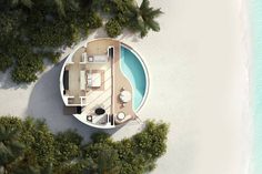 an aerial view of a house on the beach with palm trees surrounding it and blue water