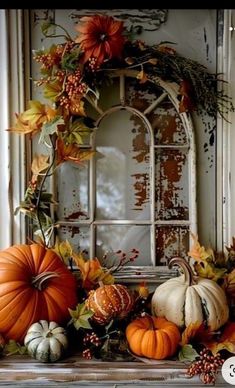 pumpkins and gourds sit on a mantle in front of an old window