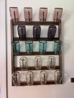 several glasses are lined up on a shelf in front of a door with an old window frame