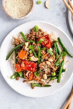 a white plate topped with rice, green beans and vegetables next to chopsticks