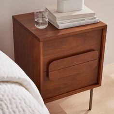 a nightstand with books and a glass on it