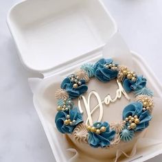 a cake in a box with the word dad written on it and decorated with blue flowers