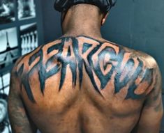 the back of a man with tattoos on his upper and lower back, which reads strength