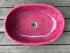 a pink sink sitting on top of a wooden table