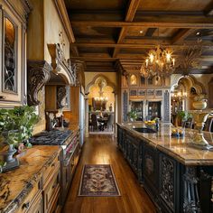 a large kitchen with wooden floors and fancy chandeliers hanging from the ceiling, along with marble counter tops