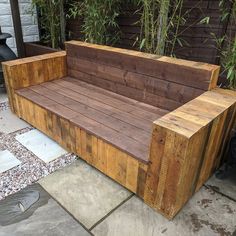 a wooden bench sitting on top of a stone floor next to a bamboo planter