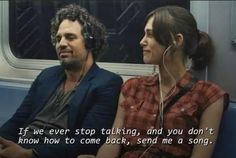 a man and woman sitting next to each other on a train with headphones in their ears