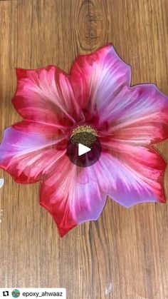 a pink flower sitting on top of a wooden table