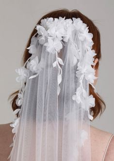 the back of a woman wearing a veil with flowers on it and white hair combs