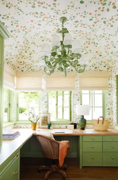 a kitchen with green cabinets and floral wallpaper on the ceiling, along with a chandelier