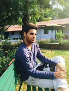 a man sitting on top of a green bench next to a lush green park area