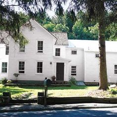 a large white house sitting on the side of a road next to a tree filled street