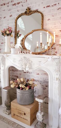 a white fireplace with flowers and candles on it in front of a mirror above the fire place