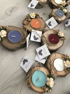 several small candles sitting on top of wooden slices with tags attached to them and flowers