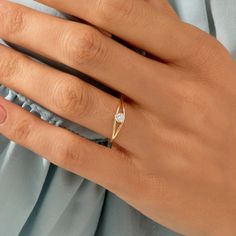 a woman's hand wearing a gold ring with a diamond in the middle and on top