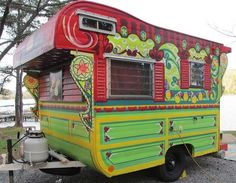 a colorfully painted trailer parked next to a body of water