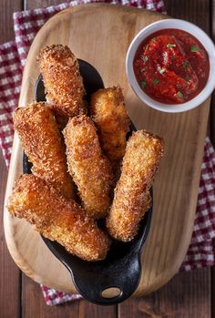 some fried food is sitting on a plate next to a bowl of ketchup