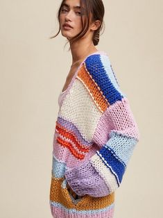 a woman is wearing a multicolored sweater