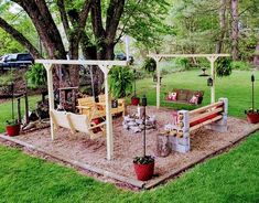 a wooden bench sitting under a tree next to a swing set and fire pit on top of a grass covered field