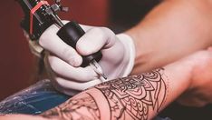 a tattoo artist working on someone's arm