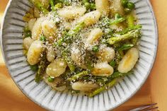 a white bowl filled with pasta and asparagus covered in parmesan cheese