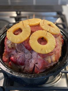 a meat dish with pineapple slices on top of it in a frying pan